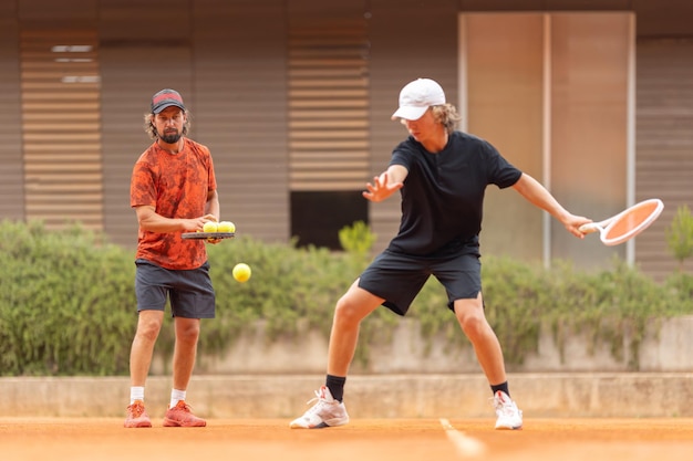 Il padre insegna a suo figlio adolescente a giocare a tennis in campo