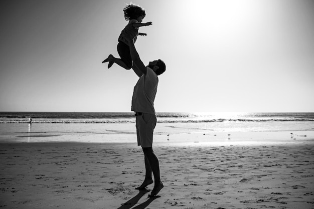 Il padre lancia il figlio contro il cielo blu papà lancia la silhouette del bambino sul concetto di amicizia al tramonto