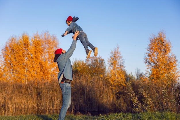 Il padre lancia suo figlio in cielo vestito con cappelli a maglia rossi in autunno