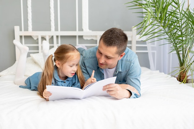 Il padre legge un libro o studia con il figlio della figlia prima di andare a letto o si diverte