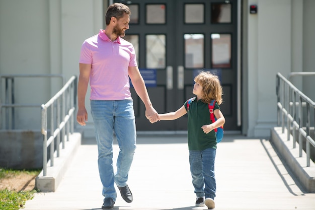 Il padre sostiene e motiva il figlio Genitore che porta il bambino a scuola L'allievo della scuola primaria va a studiare con lo zaino all'aperto Genitore con il bambino davanti ai cancelli della scuola