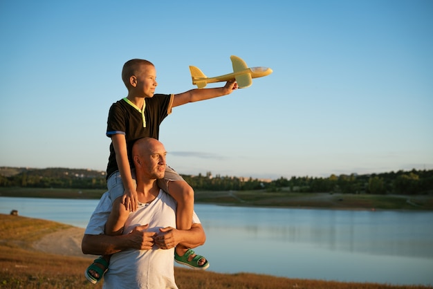 Il padre tiene il figlio sulle spalle in riva al lago