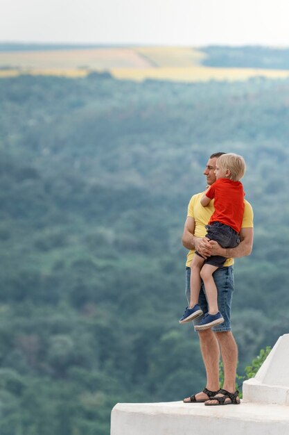 Il padre tiene in braccio il figlio Padre e figlio stanno sul ponte di osservazione e ammirano il paesaggio Cornice verticale