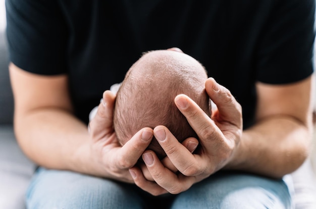 Il padre tiene in mano il neonato