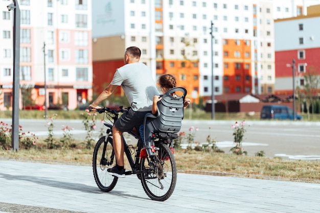 Il padre va in bicicletta la figlia piccola in un seggiolino per bambini