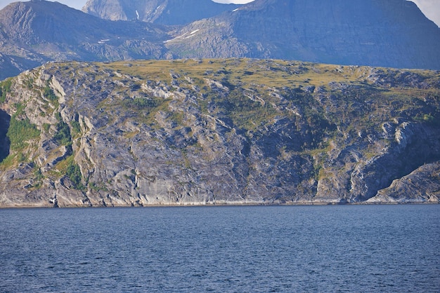 Il paesaggio di un mare calmo vicino a una montagna rocciosa Una catena di verdi colline montuose vicino a un grande lago in Norvegia Oceano pacifico in una costa selvaggia di una natura nordica scena per lo spazio della copia