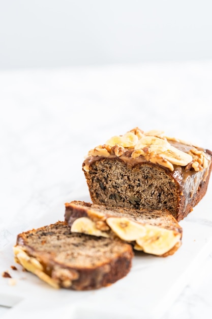 Il pane alle noci di banana affettato ha spruzzato caramello fatto in casa su un tagliere di marmo.