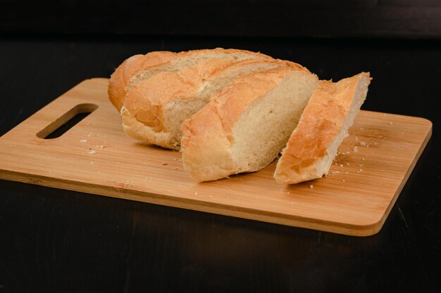 Il pane bianco affettato si trova su un tagliere su un fondo di legno