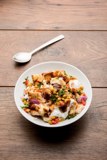 Il pane chaat, chat è un gustoso antipasto o antipasto indiano, servito in una ciotola guarnita con pomodoro, sev e coriandolo e masala. messa a fuoco selettiva