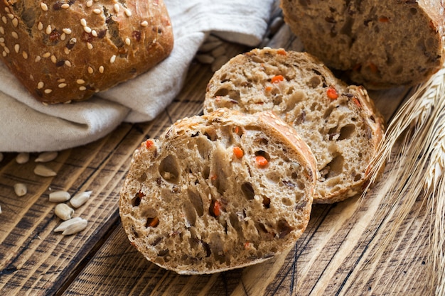 Il pane fresco con semi di girasole, semi di sesamo e lino viene tagliato a pezzi su un tagliere.