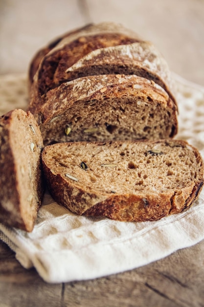 Il pane fresco marrone con i semi viene tagliato a pezzi su uno sfondo di legno vecchio. Copia, spazio vuoto per il testo