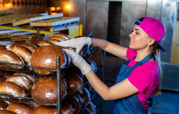 Il panettiere professionista tiene il pane in mano. Produzione industriale di pane. Pane nelle mani di un fornaio sullo sfondo di un forno industriale. Produzione industriale di pane. Avvicinamento.