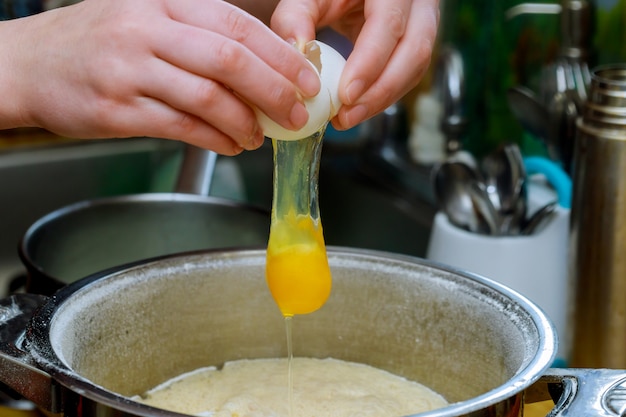 Il panettiere rompe l&#39;uovo aperto sulla farina per la preparazione dell&#39;impasto