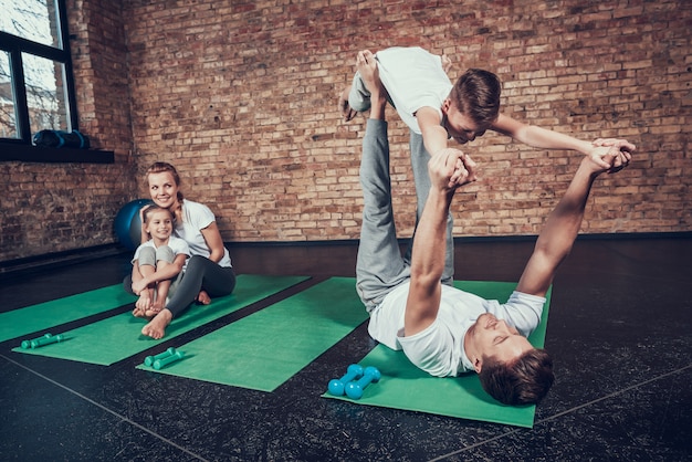 Il papà della famiglia dello sport sta equilibrando il figlio sulle gambe
