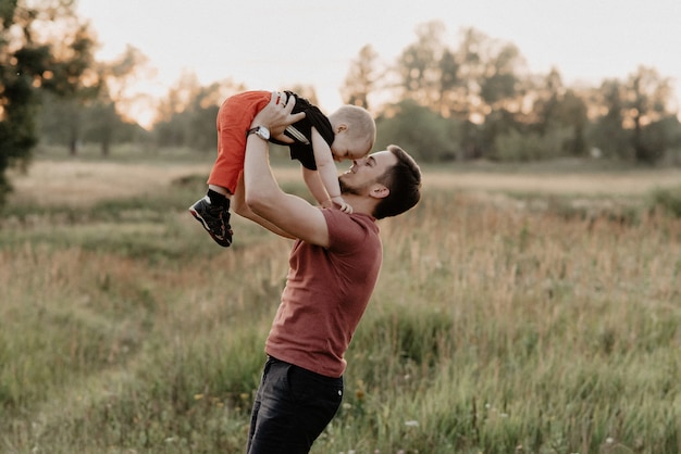 Il papà e il figlio felici sorridono e giocano nel campo al tramonto