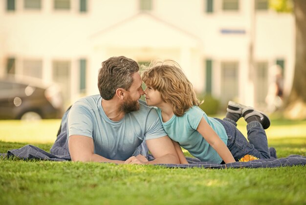 Il papà felice con il figlio si rilassa insieme sulla paternità dell'erba verde del parco