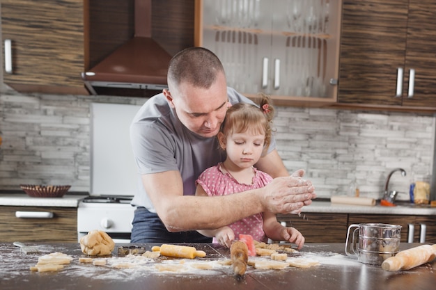 Il papà felice fa i biscotti con la sua piccola figlia setaccia la farina tra le mani