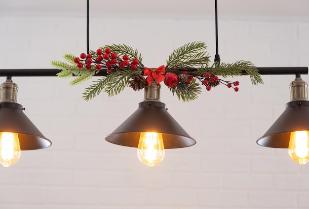 Il paralume nero in stile loft industriale è decorato con rami di abete rosso per Natale e Capodanno sullo sfondo muro di mattoni bianchi Primo piano minimalismo