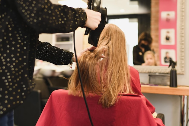 Il parrucchiere asciuga i capelli con un asciugacapelli in un salone