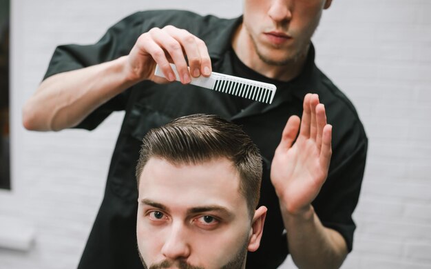 Il parrucchiere completa il taglio di capelli del cliente