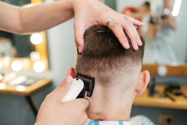 Il parrucchiere esegue un taglio di capelli da uomo Il barbiere taglia un uomo con un tagliacapelli nel salone