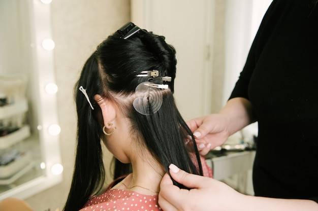 Il parrucchiere fa estensioni dei capelli a una ragazza in un salone di bellezza. Cura dei capelli professionale.