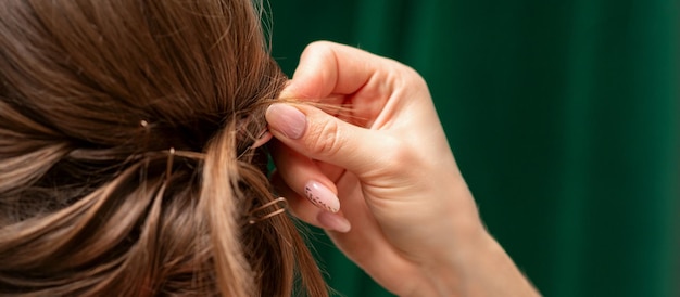 Il parrucchiere fa le acconciature per una giovane donna nel salone di bellezza da vicino.