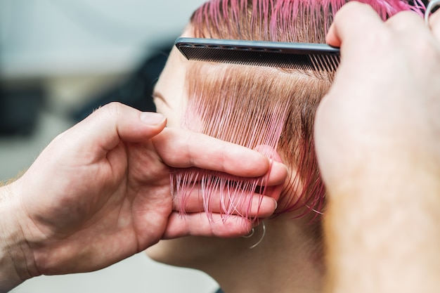 Il parrucchiere pettina i capelli della ragazza mentre taglia.