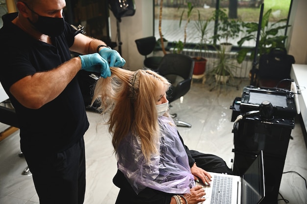 Il parrucchiere pettina i capelli delle clienti del salone di bellezza e lavora in sicurezza durante la quarantena.