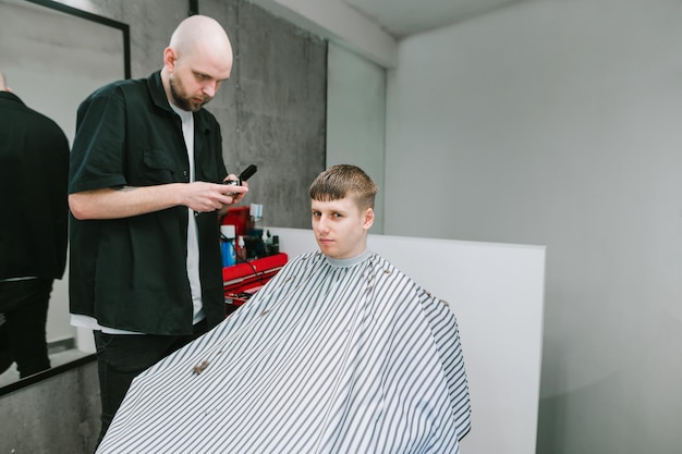 Il parrucchiere professionista taglia un giovane con un clipper e un pettine in mano