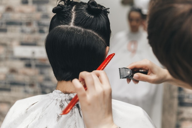 Il parrucchiere raddrizza i capelli della ragazza dopo un taglio di capelli corto