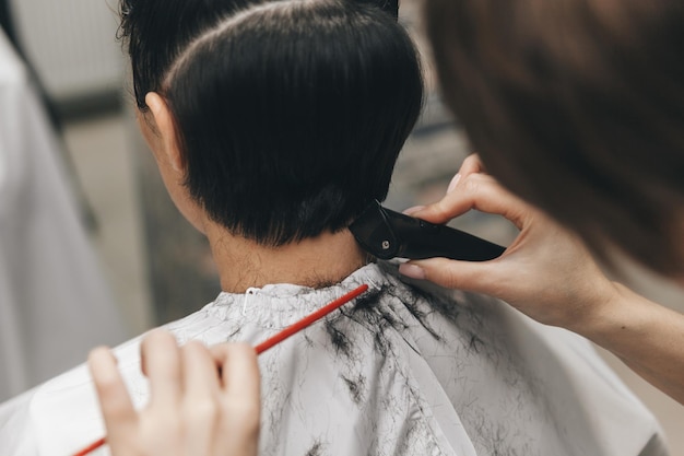 Il parrucchiere raddrizza i capelli della ragazza dopo un taglio di capelli corto