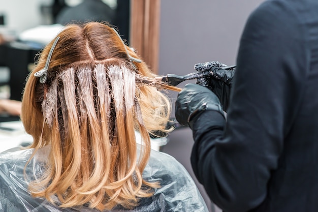 Il parrucchiere sta tingendo i capelli di una donna.