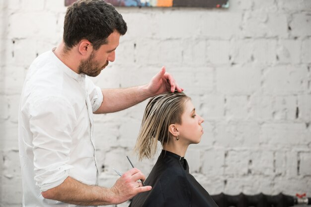 Il parrucchiere taglia i capelli con le forbici nel salone di parrucchiere professionale