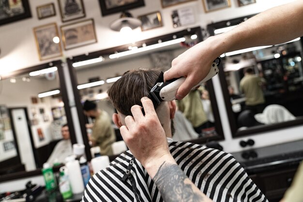 Il parrucchiere taglia i capelli del modello maschio dai capelli castani. Processo di creazione di nuova acconciatura.