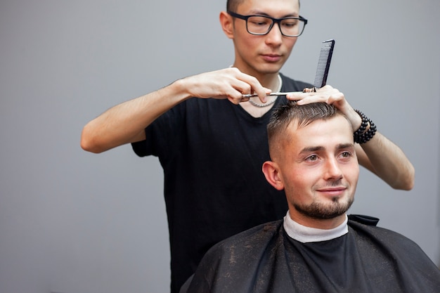 Il parrucchiere taglia i capelli di un cliente in un barbiere