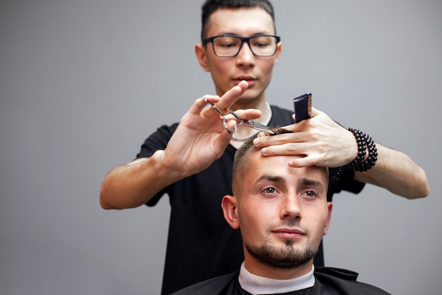 il parrucchiere taglia i capelli di un giovane in un barbiere