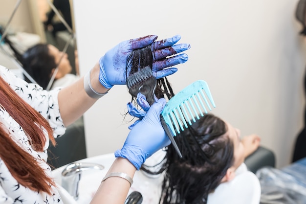 Il parrucchiere tinge i capelli di una cliente girl