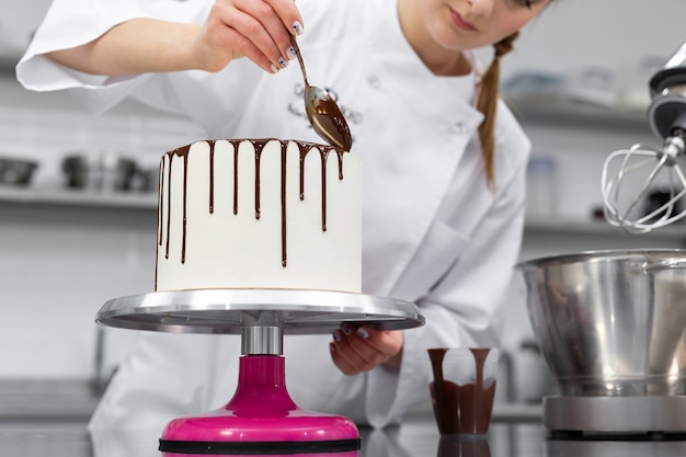 Il pasticcere decora la torta con striature di cioccolato.