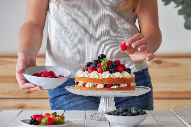 Il pasticcere decora la torta di frutti di bosco