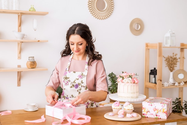 Il pasticcere della donna a casa imballa le caramelle gommosa e molle casalinghe in belle scatole. Confezione di dolci.