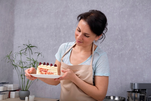 Il pasticcere della donna sta tenendo il piatto con la fetta di torta. Pasticcere cotto torta di frutta.