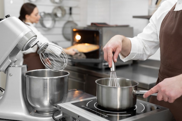 Il pasticcere maschio cucina un kuli di bacche in una casseruola per riempire una torta.