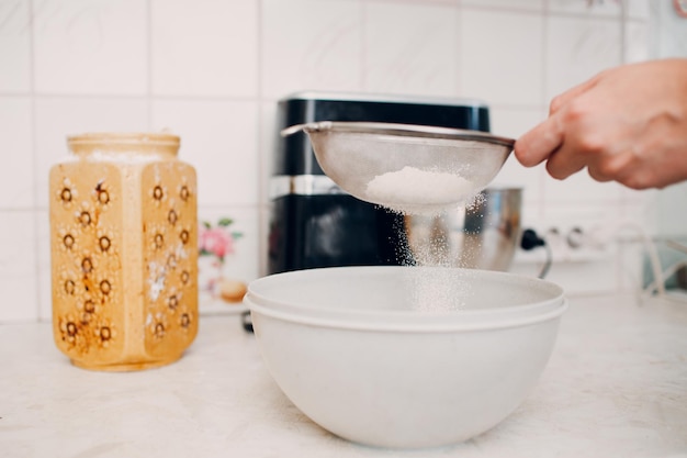 Il pasticcere setacciare versa la farina per fare la torta. Cucinare e preparare il dolce