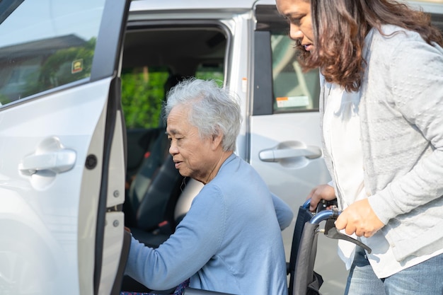 Il paziente asiatico anziano o anziano della donna della signora che si siede sulla sedia a rotelle si prepara a raggiungere il suo concetto medico forte sano dell'automobile