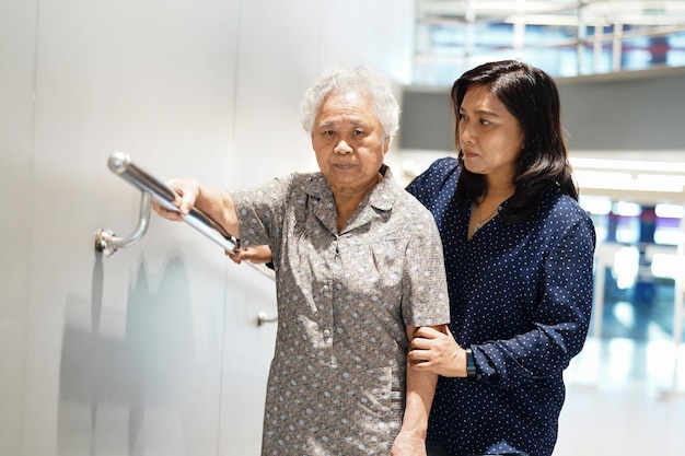 Il paziente asiatico anziano o anziano della donna della signora usa la sicurezza della maniglia della passerella del pendio con l'assistente di supporto di aiuto nel concetto medico forte sano del reparto di cura dell'ospedale