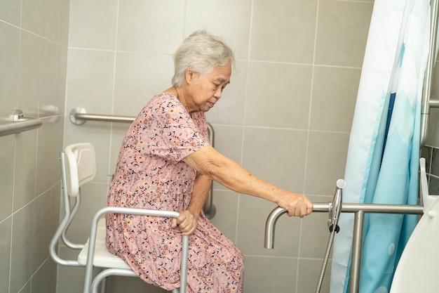 Il paziente asiatico della donna anziana usa la sicurezza della maniglia del bagno della toletta nel concetto medico forte sano del reparto di cura dell'ospedale