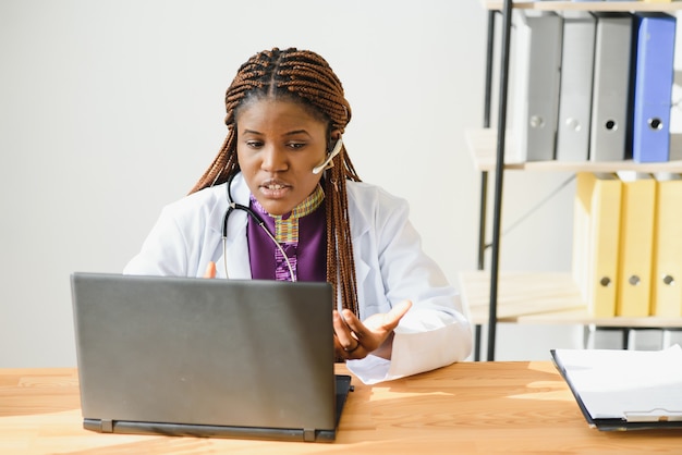 Il paziente consultantesi del medico femminile africano effettua la videochiamata in linea della webcam sul laptop.