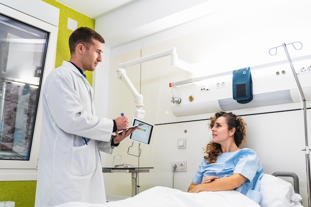 Il paziente impegnato ascolta il medico che mostra i dati medici su un tablet all'interno di una moderna stanza d'ospedale