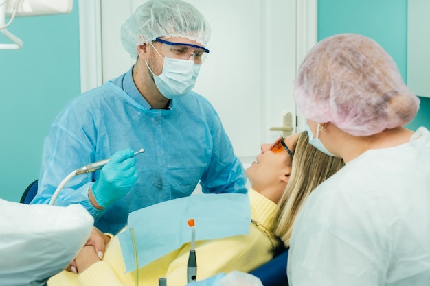 Il paziente sorride sulla poltrona del dentista in una maschera protettiva e uno strumento prima del trattamento in th